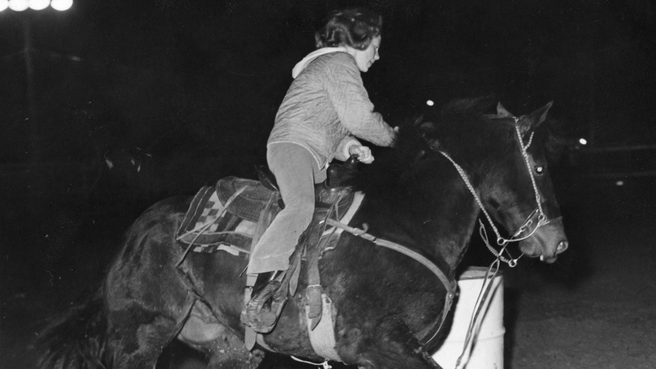 Reba rides horse around barrel 